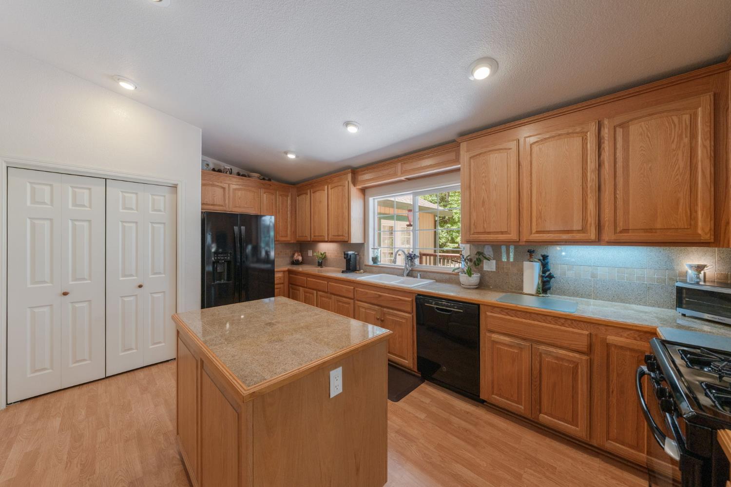 6221 Speckled Road Pollock Pines, CA 95726 - Photo 10 of 41 a kitchen with a refrigerator a sink dishwasher with wooden cabinets and floor