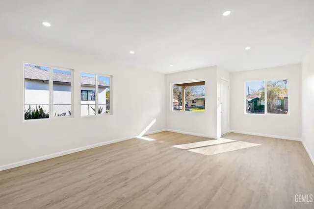 a view of an empty room with window and wooden floor