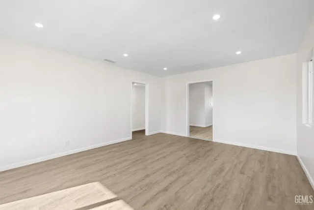 a view of an empty room with wooden floor and closet