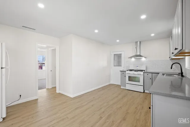 a kitchen with granite countertop a stove a sink and a refrigerator