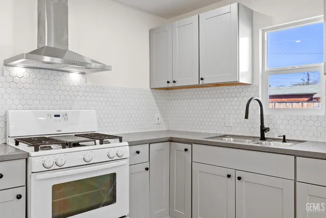 a kitchen with granite countertop a sink a stove and cabinets