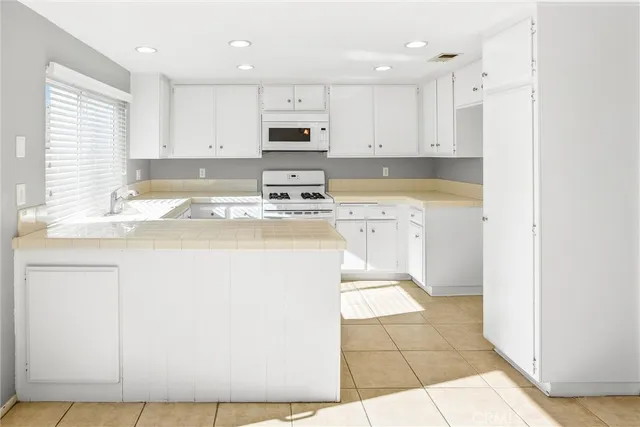 a kitchen with stainless steel appliances granite countertop a sink a stove a refrigerator and white cabinets