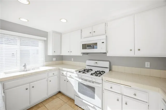 a kitchen with cabinets appliances a sink and a window