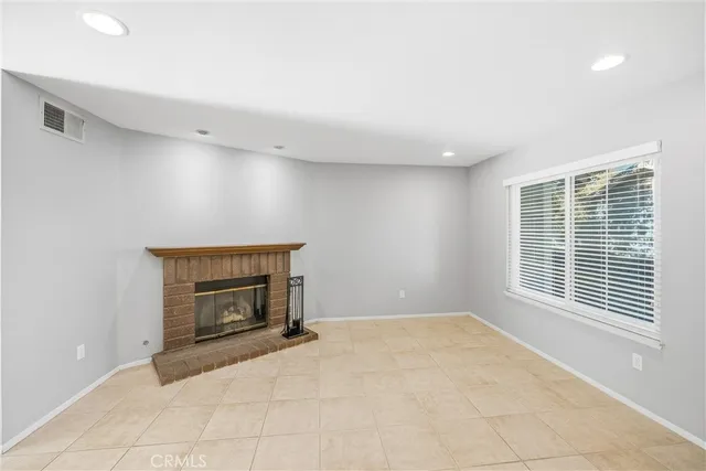 a view of an empty room with a window and fireplace
