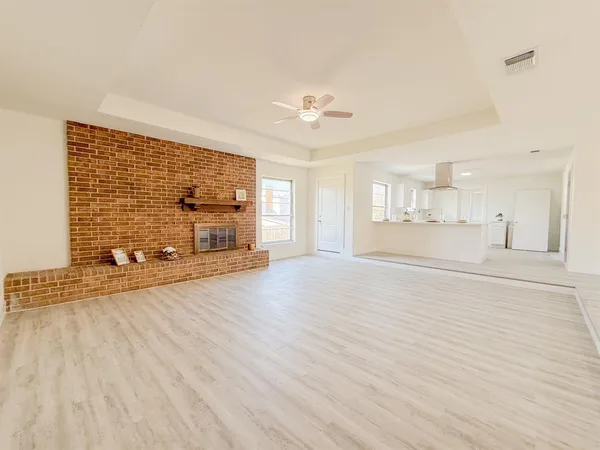 a view of a livingroom with wooden floor a ceiling fan and windows