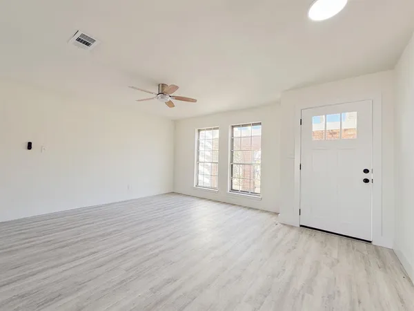 a view of an empty room with a window and wooden floor