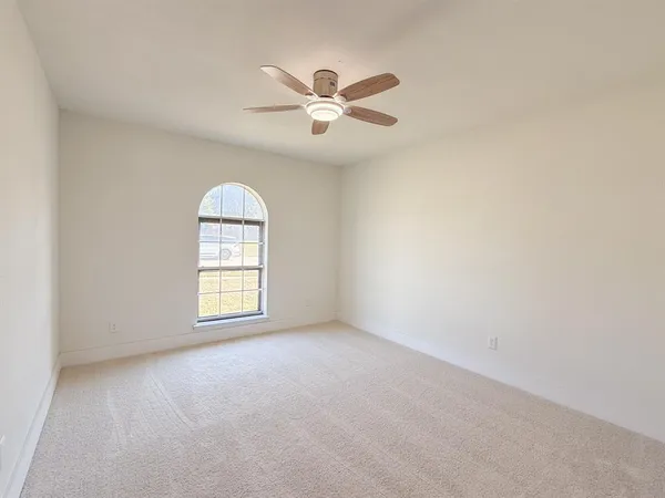 an empty room with windows and ceiling fan