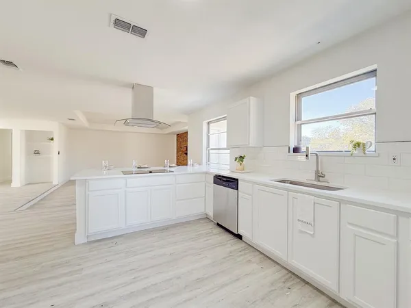 a large white kitchen with white cabinets and wooden floor
