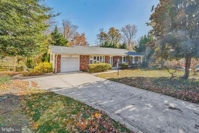 a view of a house with a yard and large trees