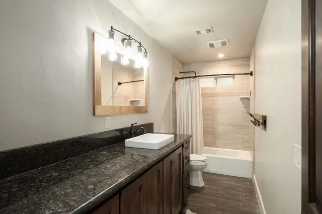 a bathroom with a granite countertop sink toilet and shower
