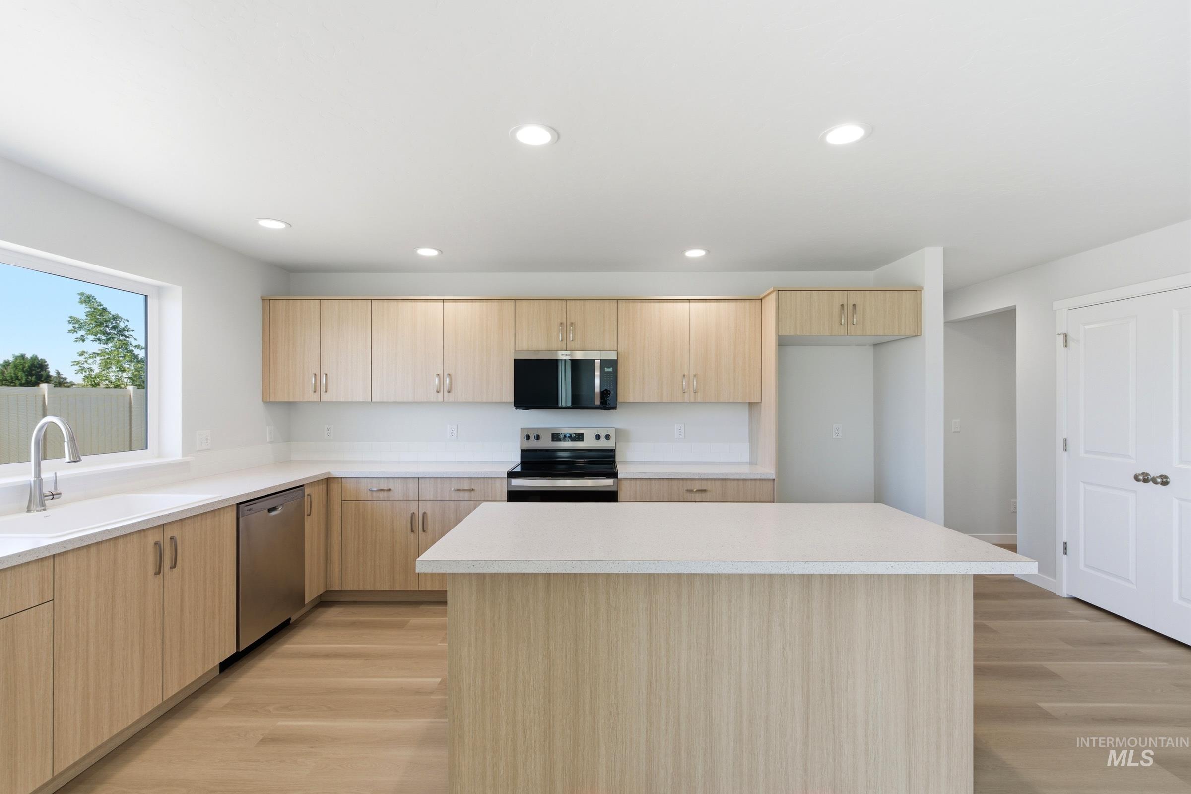 13677 Redway Court Caldwell, ID 83607 - Photo 3 of 35 Modern kitchen featuring light wood-finish cabinetry, white countertops, stainless steel appliances, a center island, and wood-finish flooring