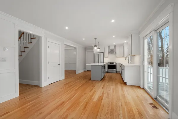 a view of a living room kitchen with stainless steel appliances wooden floor and a large window