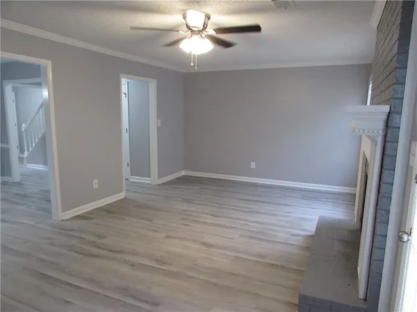 an empty room with wooden floor fireplace cabinet and windows