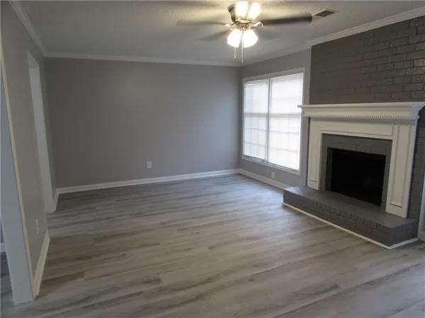 a view of an empty room with wooden floor fireplace and a window