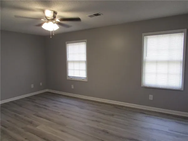 a view of an empty room with a window and wooden floor