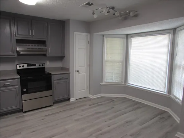 a kitchen with cabinets stainless steel appliances and wooden floor