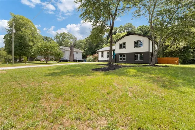 a view of a house with a big yard and large trees