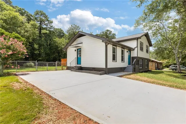 a view of a house with a yard and large tree