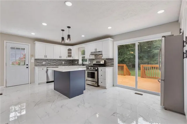 a kitchen with granite countertop a stove and a white cabinets