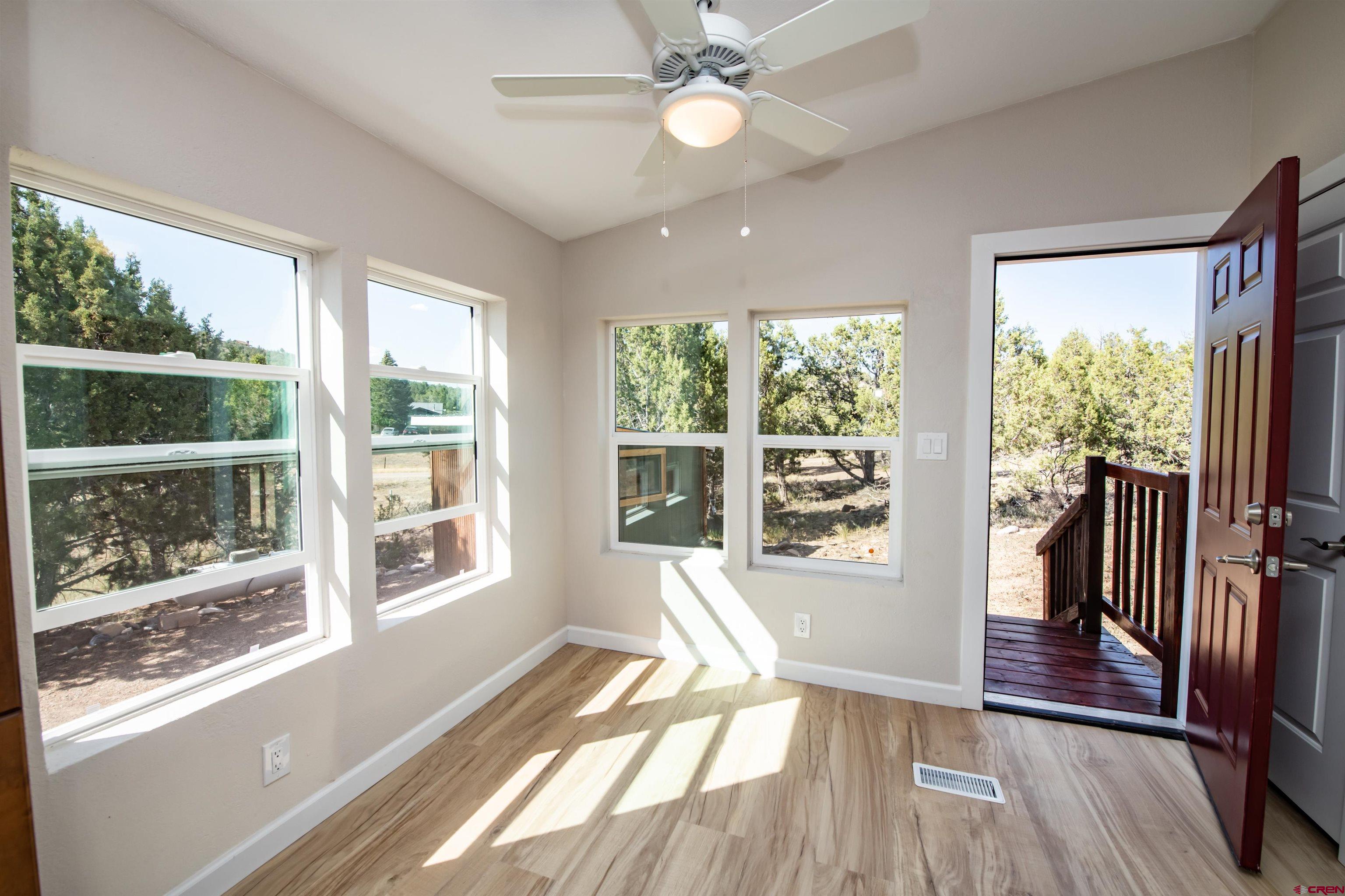 475 Run Around Road Arboles, CO 81121 - Photo 11 of 40 a view of a big room with wooden floor a ceiling fan and windows