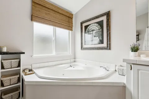 a spacious bathroom with a tub sink and mirror