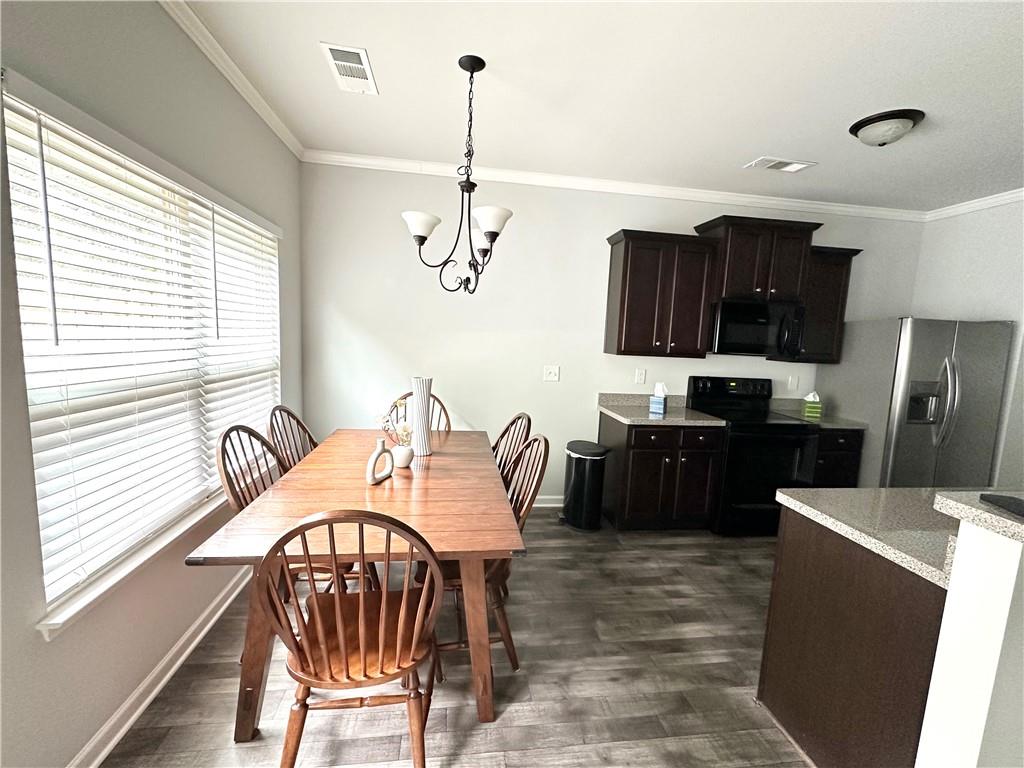 853 Ash Street Canton, GA 30114 - Photo 6 of 23 a kitchen with stainless steel appliances kitchen island granite countertop a refrigerator a stove a sink a dining table and chairs with wooden floor