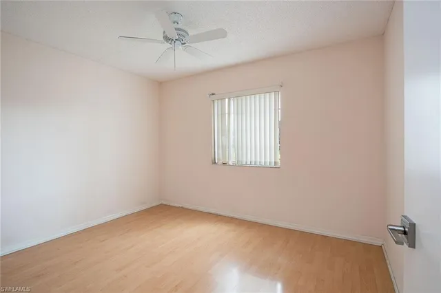 an empty room with a window and a ceiling fan
