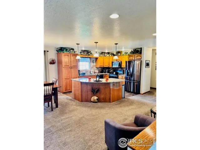 a kitchen with stainless steel appliances granite countertop a refrigerator a sink dishwasher and wooden cabinets with wooden floor