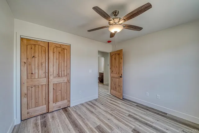 an empty room with wooden floor closet and windows