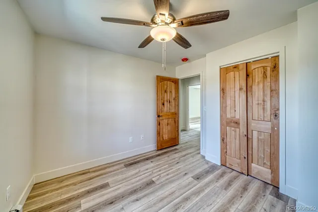 an empty room with wooden floor fan and windows