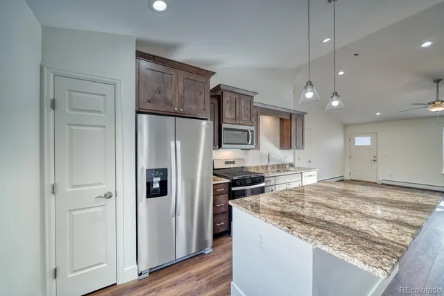 a kitchen with stainless steel appliances granite countertop a refrigerator and a stove top oven