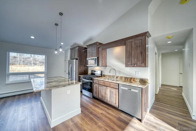 a large kitchen with stainless steel appliances granite countertop a lot of counter space and wooden floors