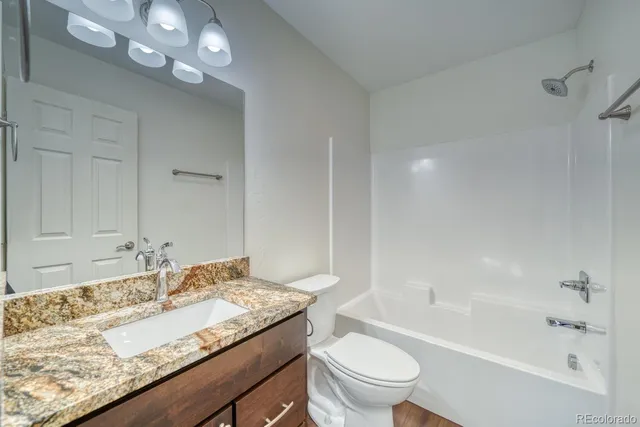 a bathroom with a granite countertop sink a toilet and bathtub