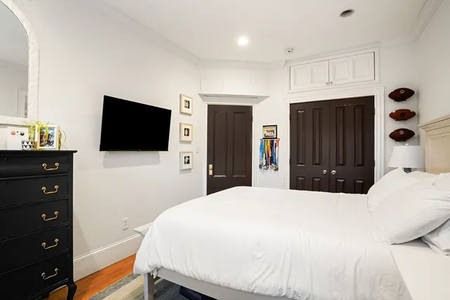 a bedroom with a bed and a flat tv screen on dresser