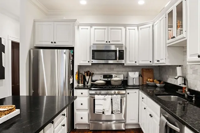 a kitchen with stainless steel appliances granite countertop a refrigerator a stove and a sink