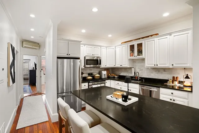 a kitchen with stainless steel appliances granite countertop a refrigerator a stove a sink a stove and white cabinets with wooden floor