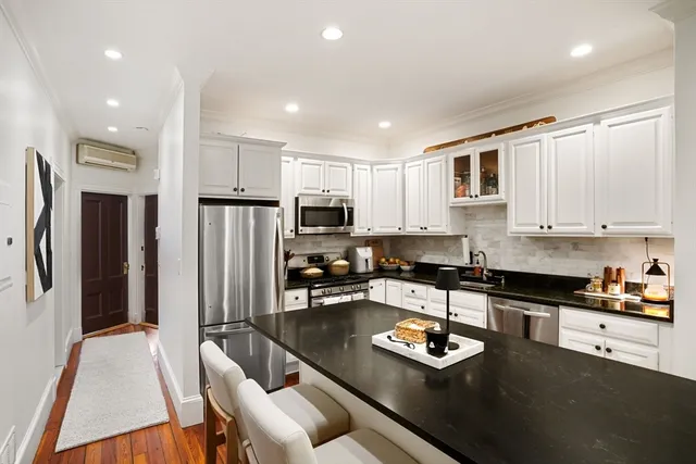 a kitchen with stainless steel appliances granite countertop a refrigerator a stove a sink a stove and white cabinets with wooden floor