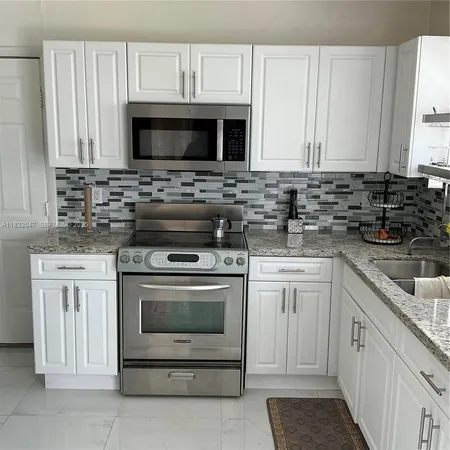a kitchen with white cabinets and black appliances