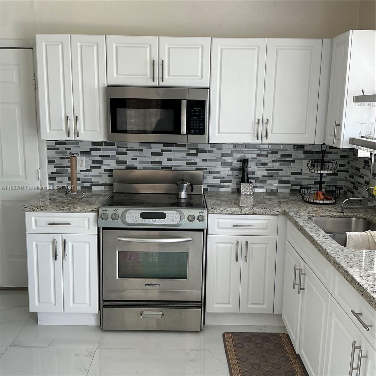 1924 Northwest 35th Street Miami, FL 33142 - Photo 17 of 29 a kitchen with white cabinets and black appliances