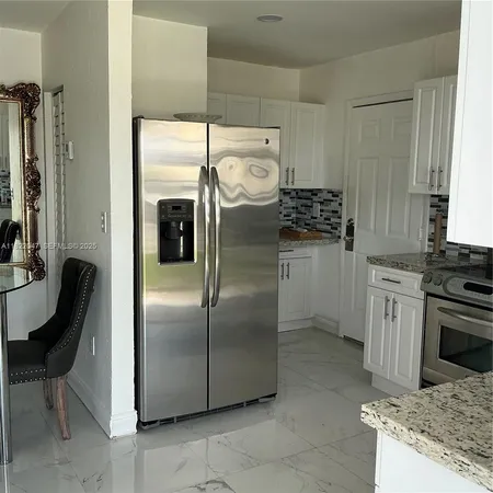 a kitchen with stainless steel appliances granite countertop a refrigerator a stove and a sink with large window