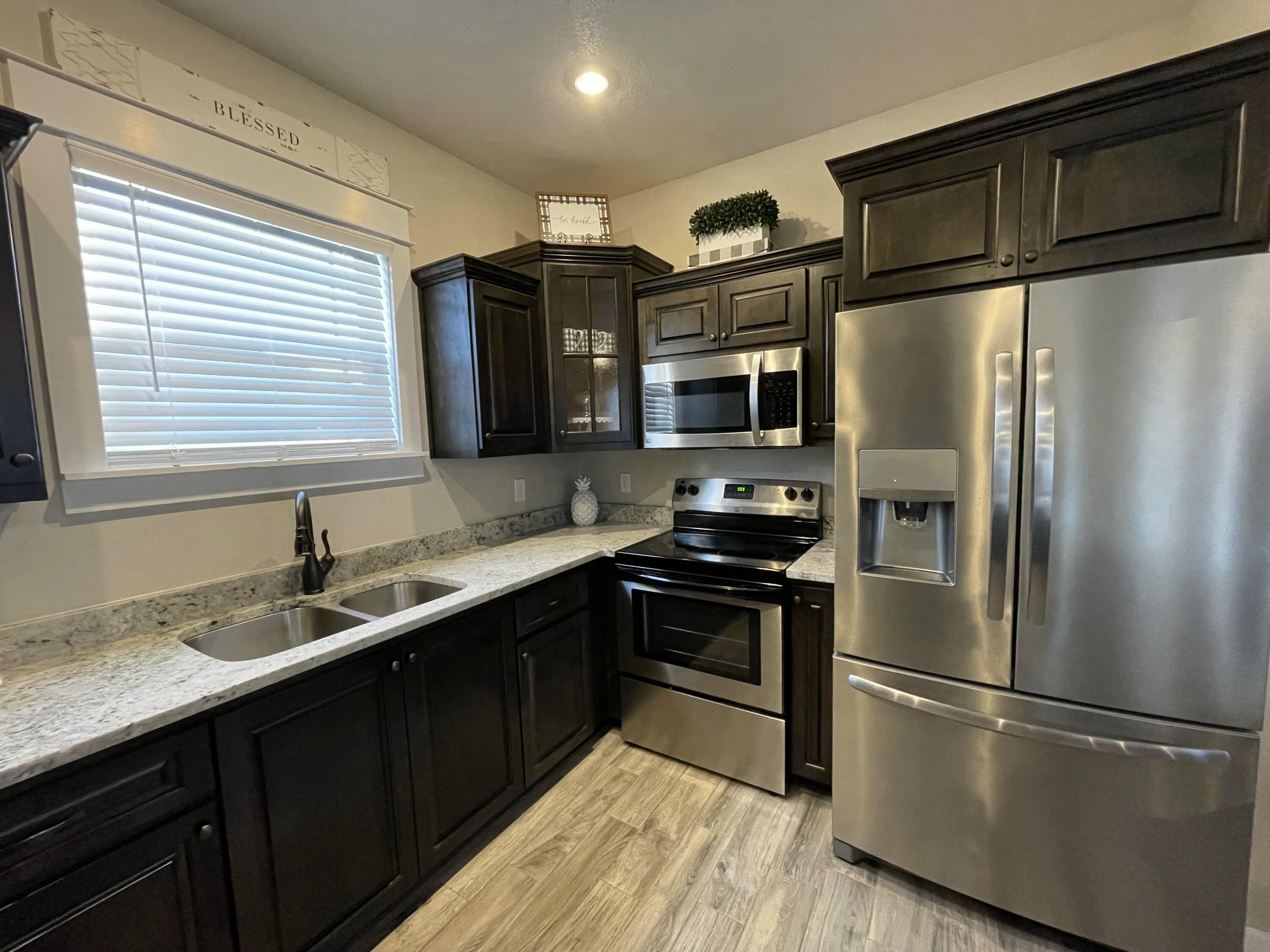 4087 Happy Trails Road Crestview, FL 32539 - Photo 11 of 30 a kitchen with stainless steel appliances granite countertop a refrigerator a sink a stove a microwave and wooden floors