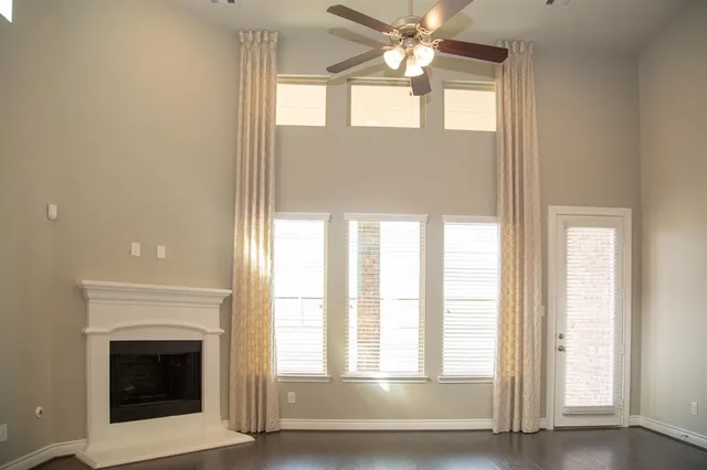 a view of an empty room with chandelier fan and fire place
