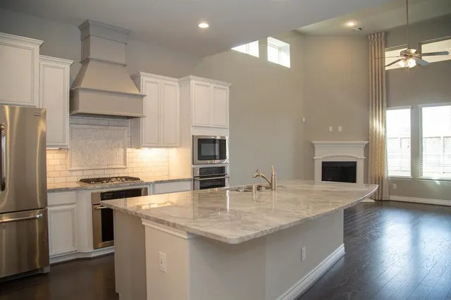 a kitchen with granite countertop a sink stainless steel appliances and cabinets
