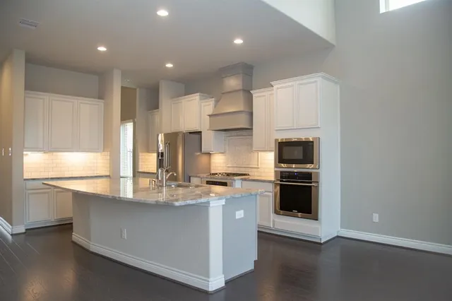 a kitchen with stainless steel appliances granite countertop a stove a sink and a refrigerator