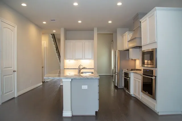 a kitchen with stainless steel appliances granite countertop a refrigerator a stove and a sink