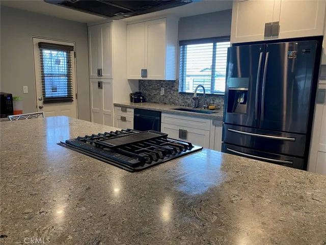 a kitchen with granite countertop a refrigerator stove and sink