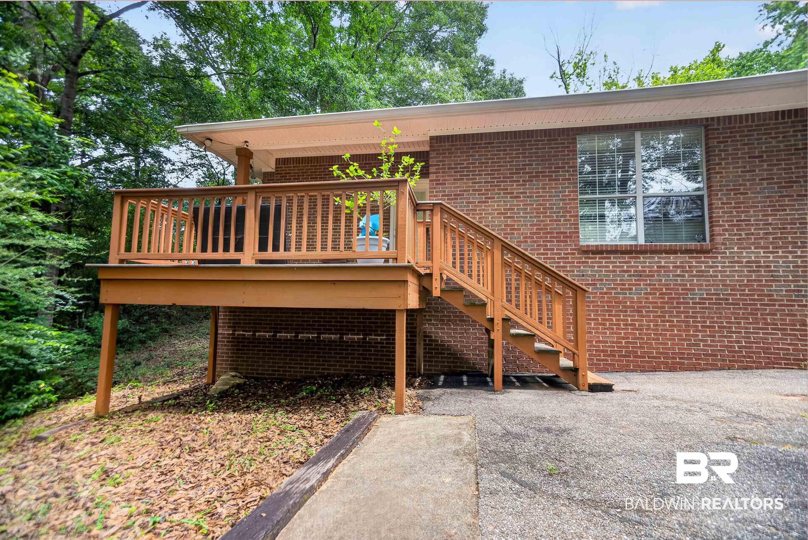 5913 Antoine Road Mobile, AL 36693 - Photo 27 of 33 Brick exterior featuring an elevated wood deck with stairs, a covered porch, and a large window