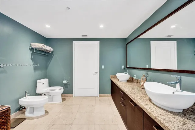 a bathroom with a granite countertop bathtub sink vanity mirror and toilet