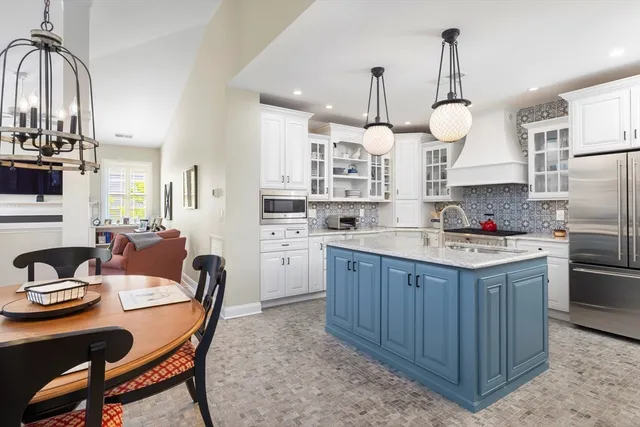 a kitchen with stainless steel appliances granite countertop a sink a stove a refrigerator cabinets a dining table and chairs