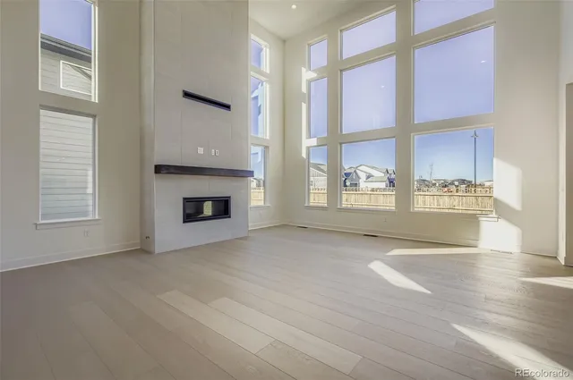 an empty room with windows and fireplace